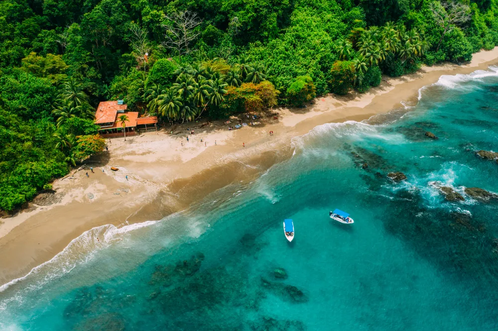 Aerial view of Costa Rican island, Isla del Cano, with boats on the turquoise water and golden sand with trees