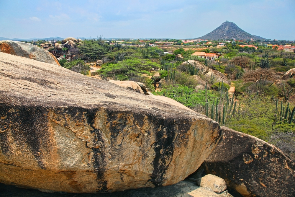 View of Aruba's landscape in the Casibari Rocks with cacti and a mountain rising in the distance for a section answering how long isa flight to Aruba with 1 stop