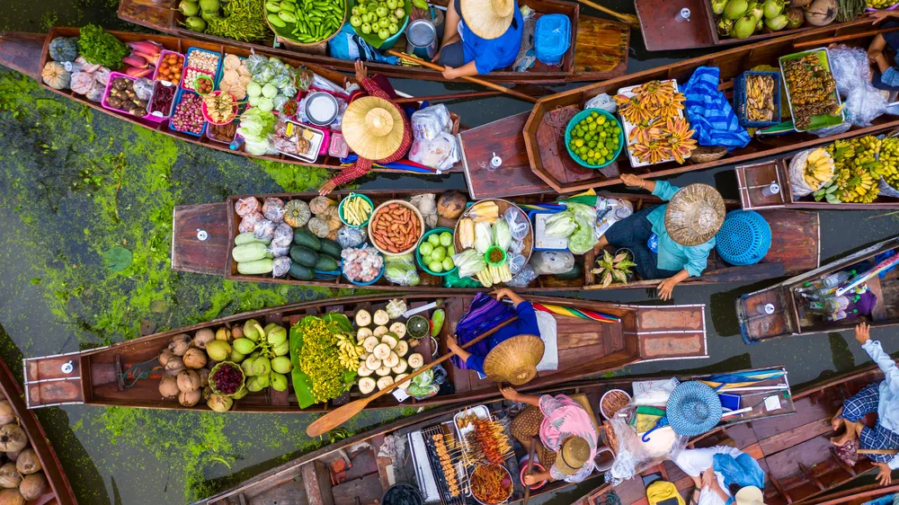 Aerial view of the Thai floating market, Damnoen Saduak, with boats holding goods for sale as we explain how long is a flight to Thailand from the US