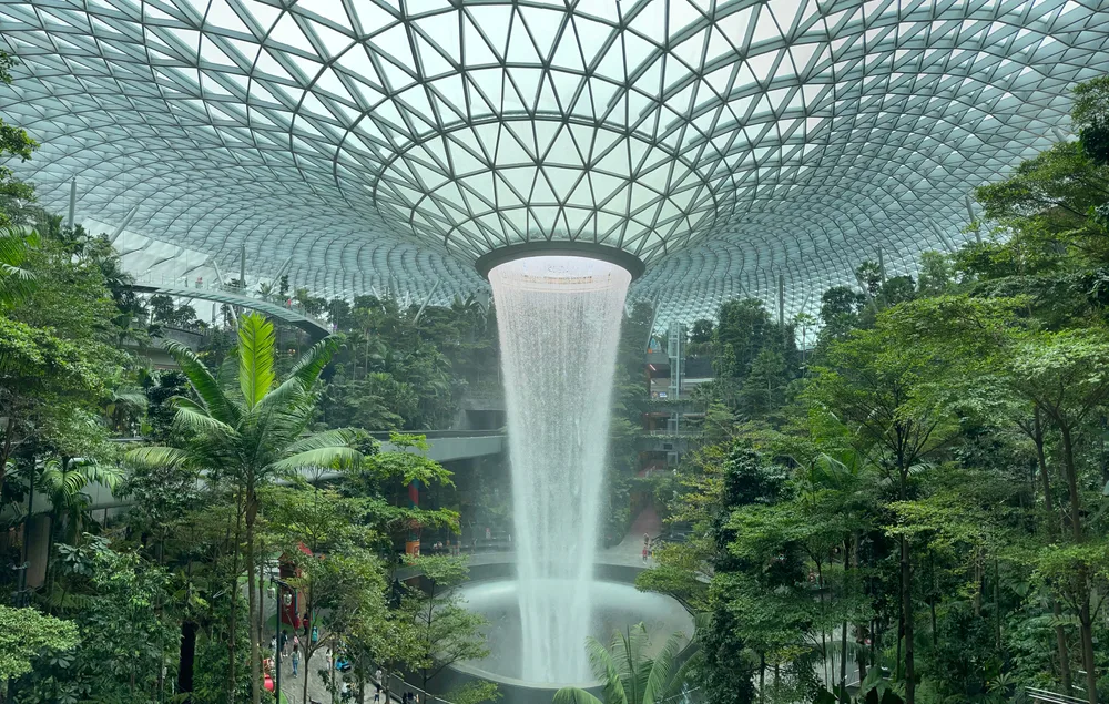 A famous Changi Jewel Airport where a large fountain structure pouring water from the ceiling, a image for an article about trip cost to Singapore.