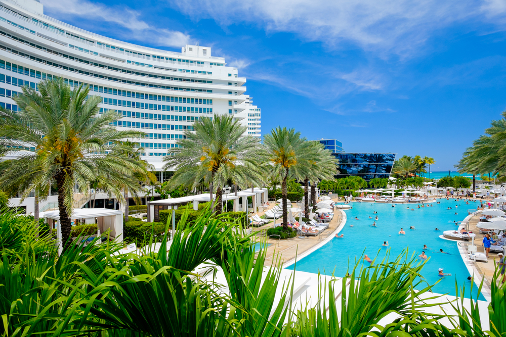 A luxurious hotel building with a large swimming pool and palm trees.
