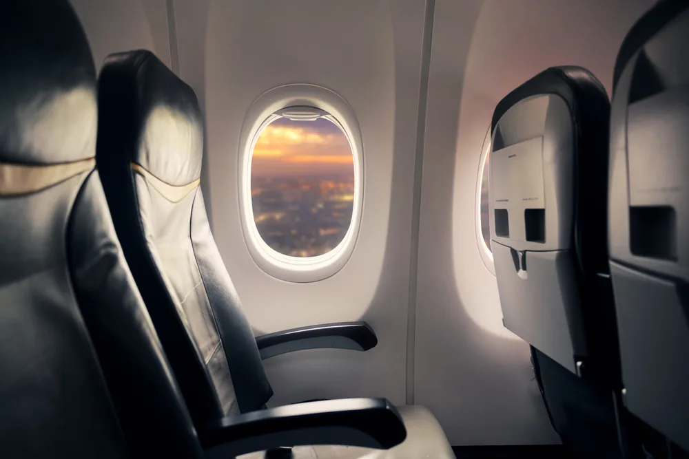 Empty airplane window seat in the front seen with a sunset view for a guide showing how to get the best seat on a plane
