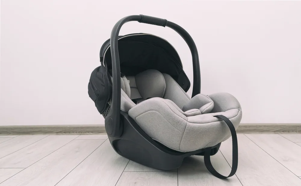An empty car seat placed on the floor, a concept image for an article about traveling with a car seat.