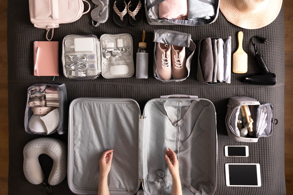 Above view of woman packing according to the international travel checklist using the Konmari method with organized packing cubes in luggage
