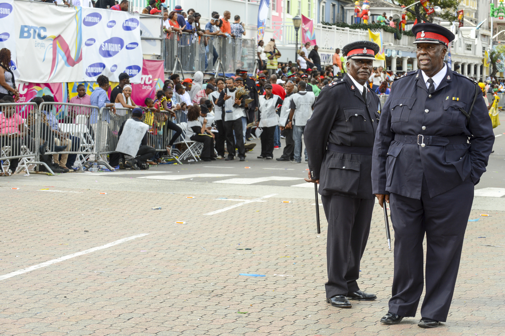 Two police officer in their uniform guarding a side of the street during a festival.
