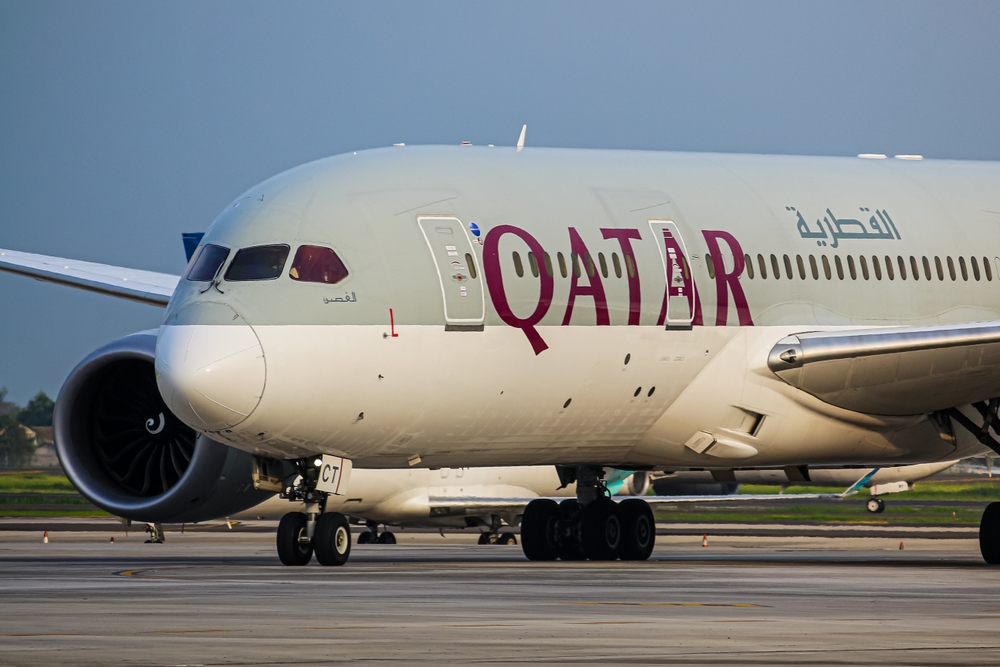 A huge airplane that has arabic writings and the name QATAR. 