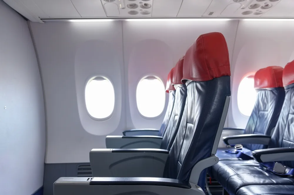 Image of plane seats in the first row showing the concept of the question what is a bulkhead seat and cons associated with little legroom when a wall partition is present on a plane