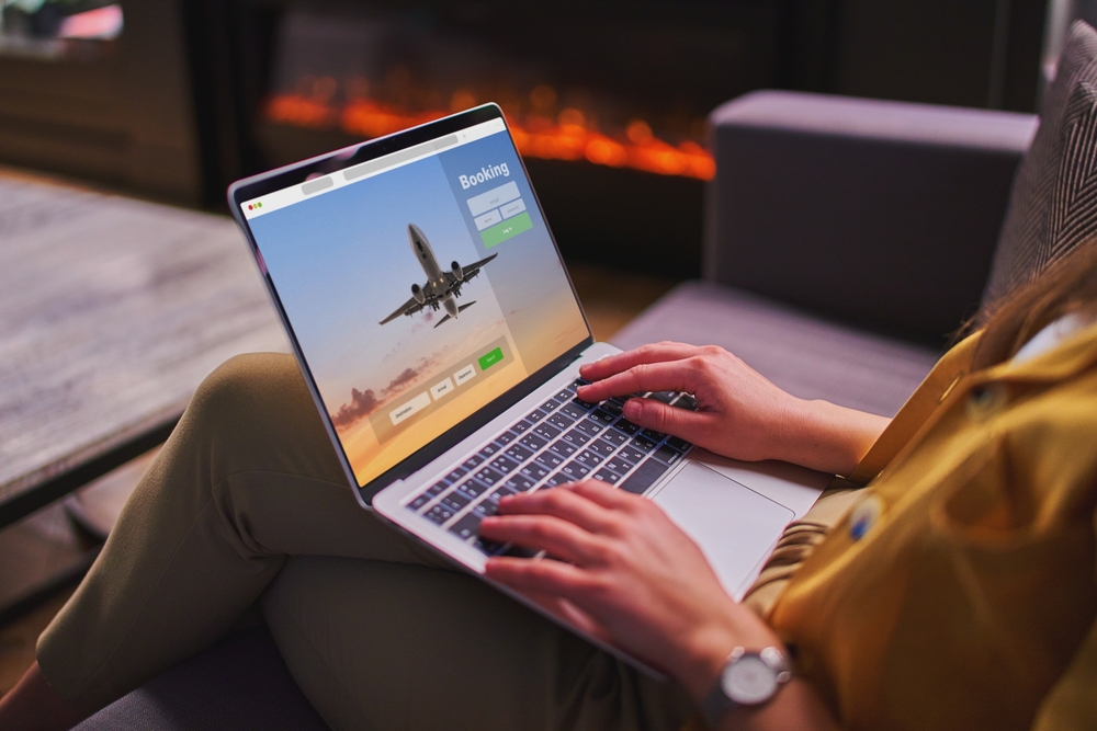 Person visits a flight booking website on a laptop to make reservations for an international trip as they check off items on the international travel checklist