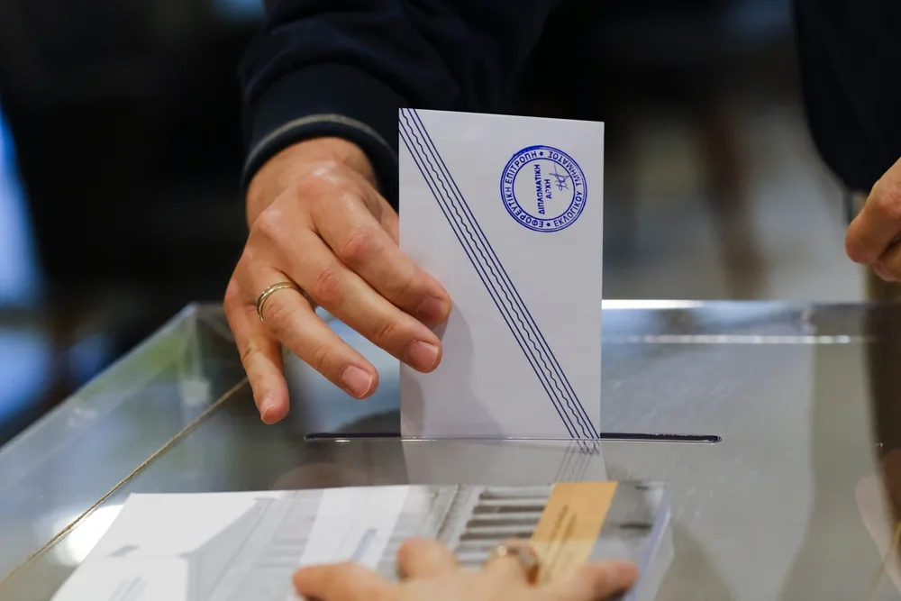 A person casting a vote in a ballot box, a concept image about compulsory voting in Greece, an item on the list of facts about Greece.