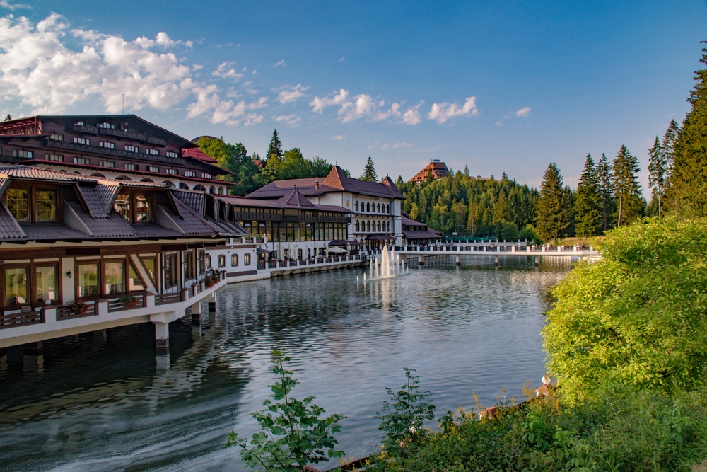 A hotel built on the lake, and in background is a forest. 