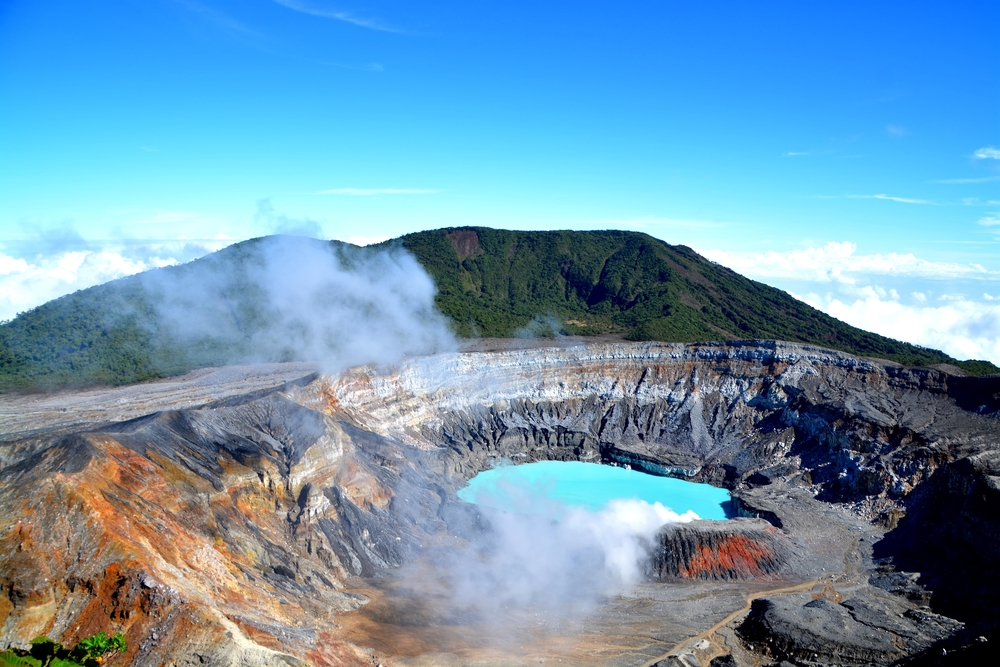 Aerial shot of the Poas volcano crater and lagoon with steam rising on a beautiful day for a piece asking how long is a flight to Costa Rica with 2 stops?