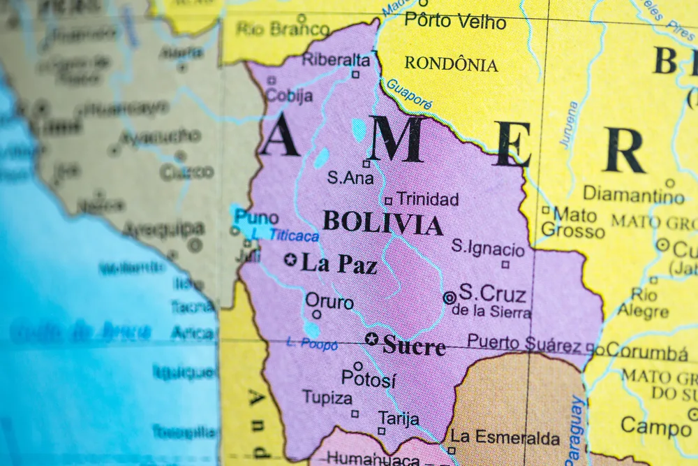 A map of Bolivia blot out on pink showing one of the many facts about Bolivia having two capitals, Sucre and La Paz.