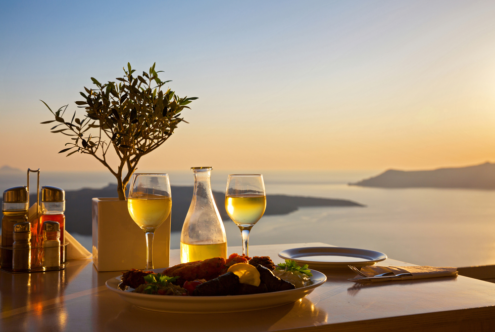A romantic meal with wine and a view of the ocean during sunset.