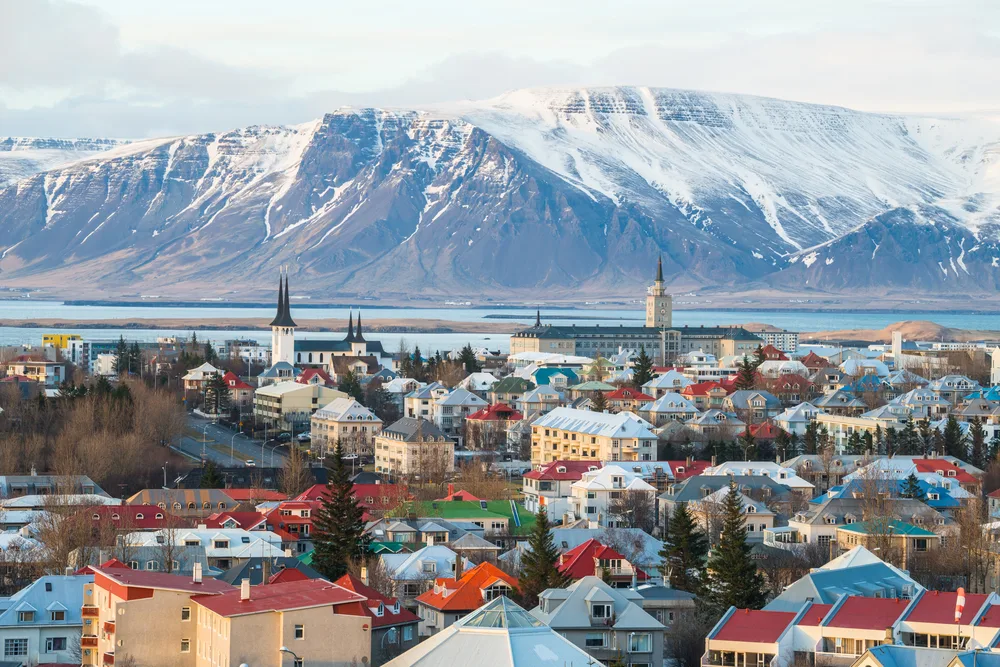 Aerial view of mountain scenery and colorful buildings in Reykjavik, Iceland, which is the #2 cheapest place to fly into Europe during the peak summer season