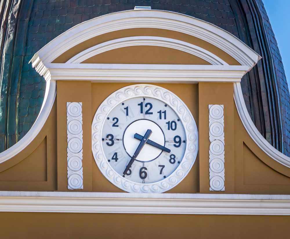 A clock on top of an old building which is arranged backwards and moving backwards. 