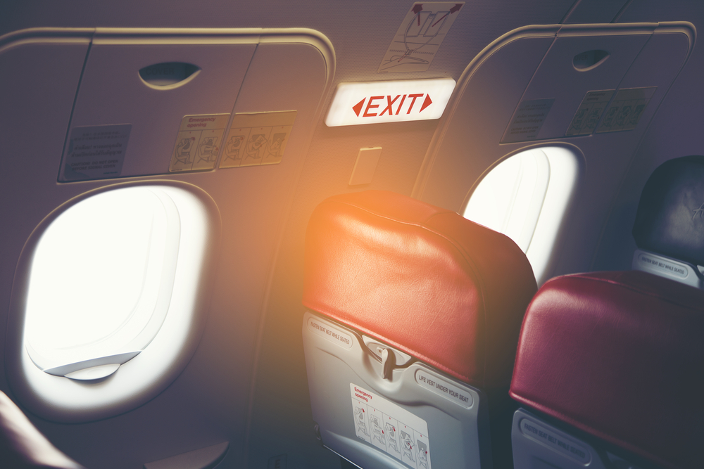 View of the plane's Exit sign in the exit row where we explain how to get the best seat on a plane with more legroom in the back