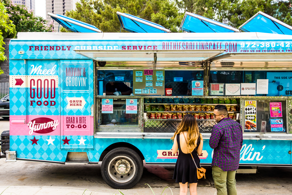 A couple buying at a sky blue food truck, a section image in an article about trip to Texas cost.