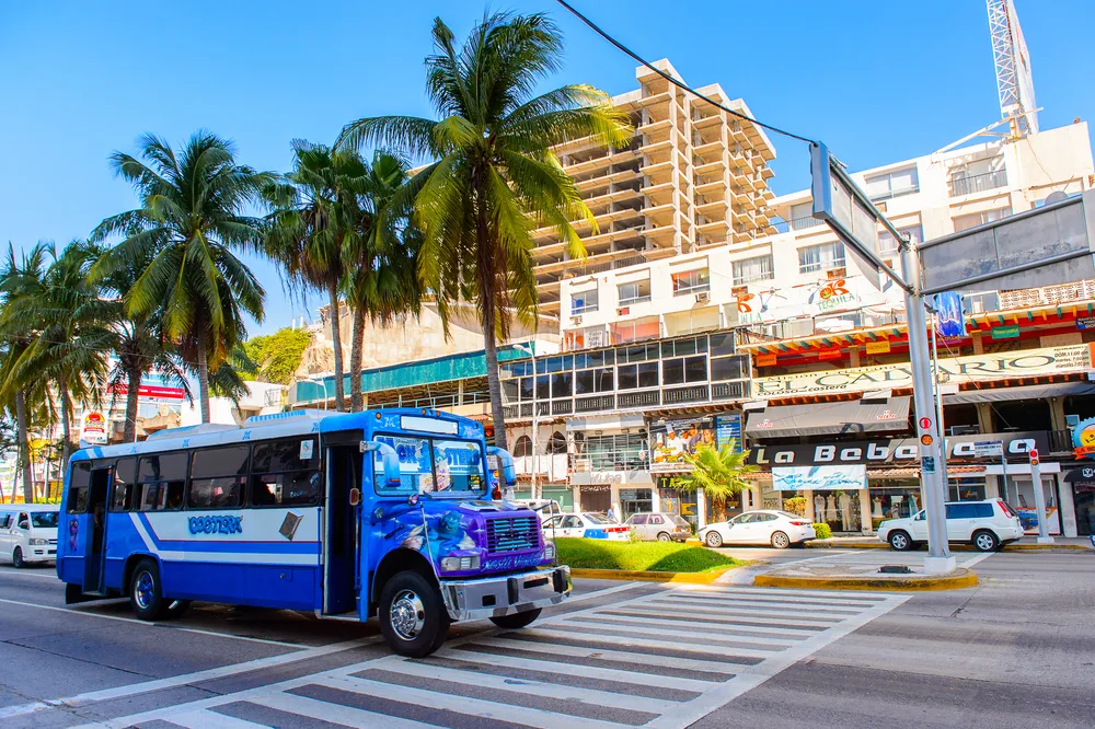 Neat view of a blue bus crossing a downtown crosswalk during the overall best time to visit Acapulco, its winter