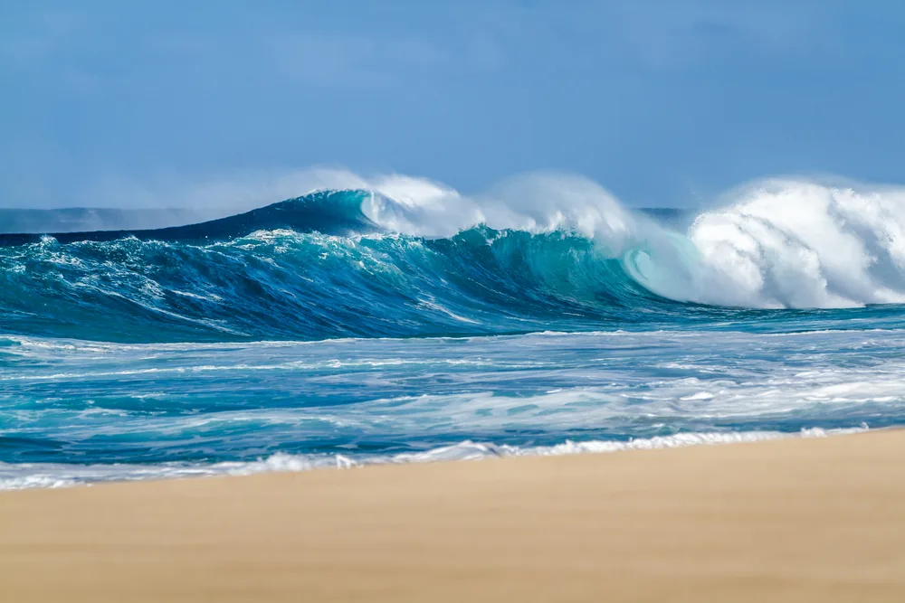 Huge wave curling on the shore of North Shore, Oahu in Hawaii for an FAQ section in a guide answering how long is a flight to Hawaii