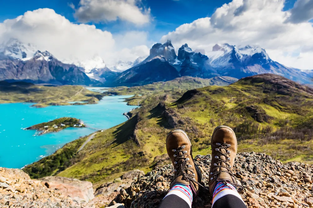 A boots in the foreground of a photo where in background can be seen tall and icy mountains. 