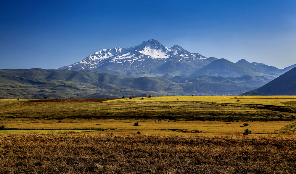 A very tall mountain with icy peaks photographed from the plains. 