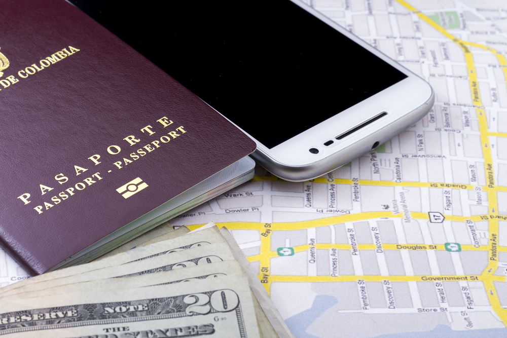 A Colombian passport, a phone, and money placed above a map.