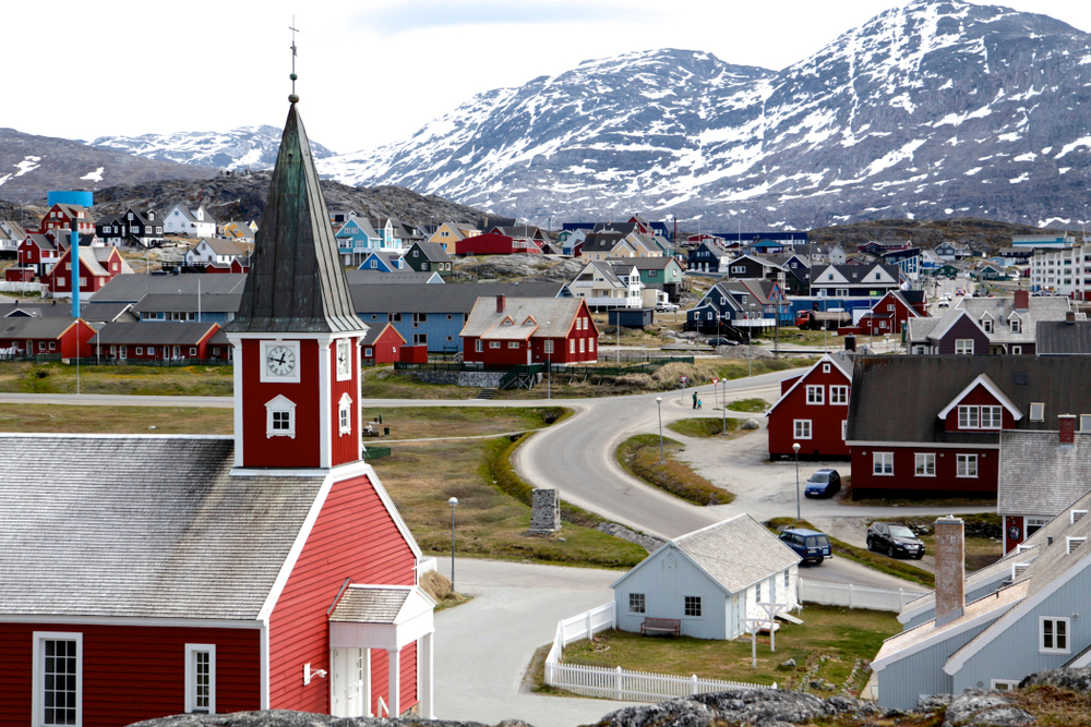 An area with several houses in Nuuk Centrum, one of our picks on the best areas to stay in Greenland, the town is in a cold region where at a distance are tall icy mountains.