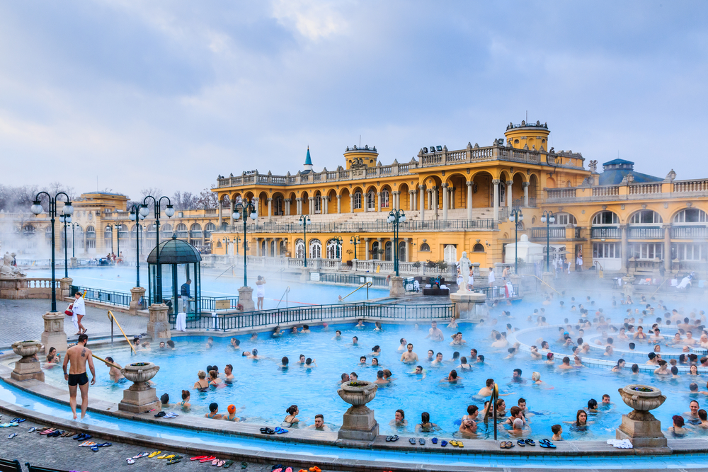 Many people enjoying a huge hot bath inside a resort. 