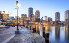 A city skyline during dusk viewed from the port during dusk of the best time to visit Boston.