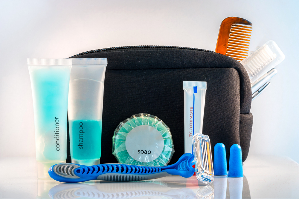 Personal care items placed in front of a small pouch, pictured for a piece on a guide titled what to pack for an Alaskan cruise.