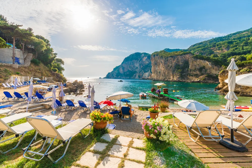 Amazing sunbeds and umbrellas on a perfectly-landscaped beach in Corfu, taken during the best month to visit Greece