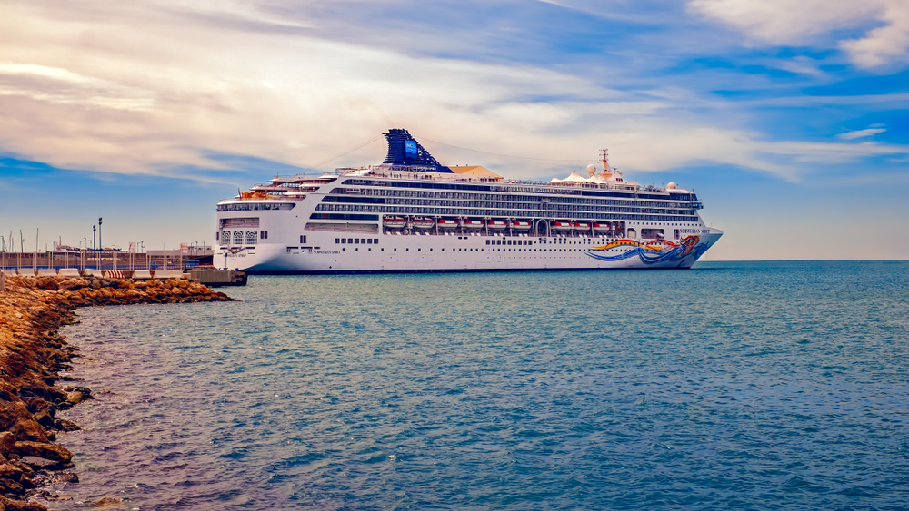 A large cruise ship docked at a pier during sunset.
