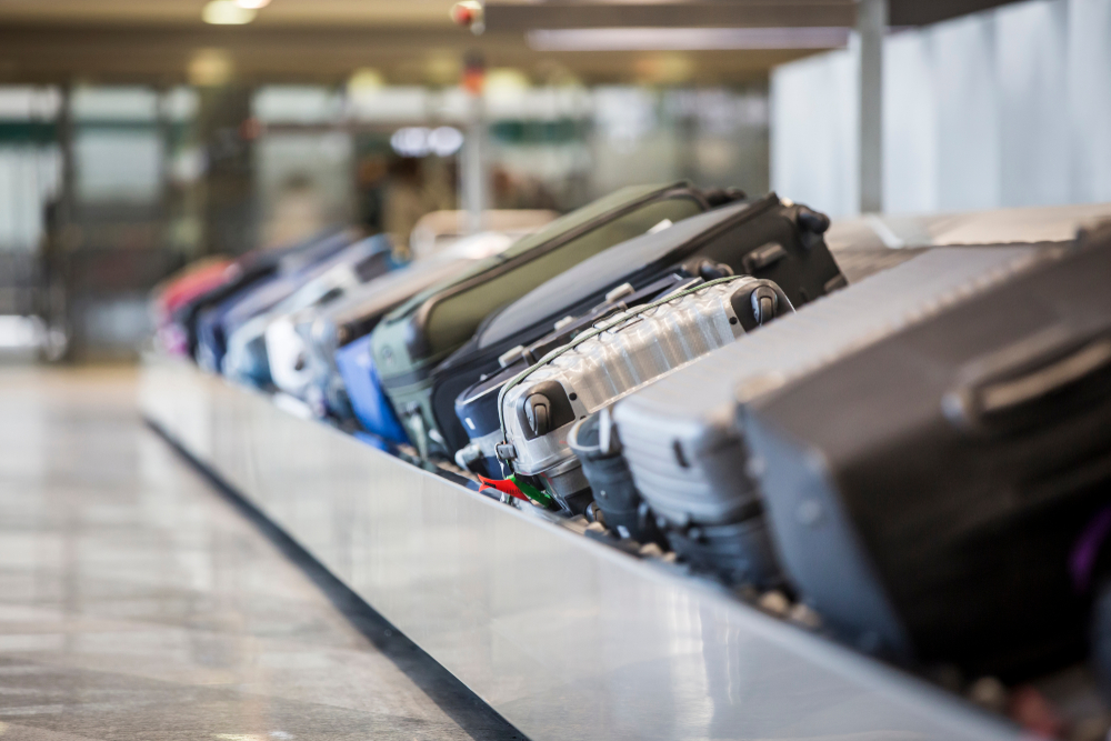 Luggage and suitcases on a baggage carousel at the airport to show the concept of what is a layover when people collect bags between connecting flights