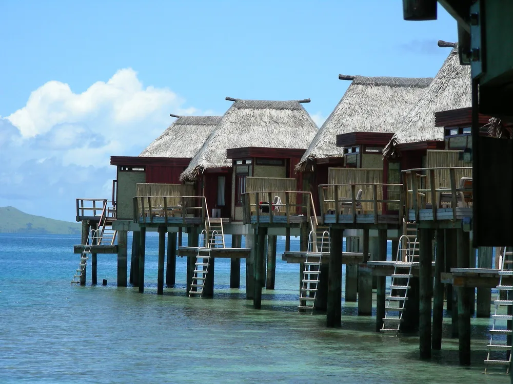 Overwater bungalows in Fiji in a line on a beautiful day for a section answering are there direct flights to Fiji?