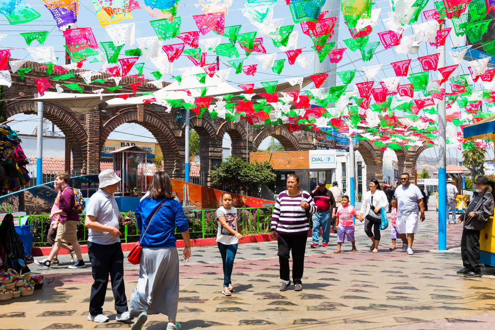 People walking on street where vibrant festival banners are hanging from above. 