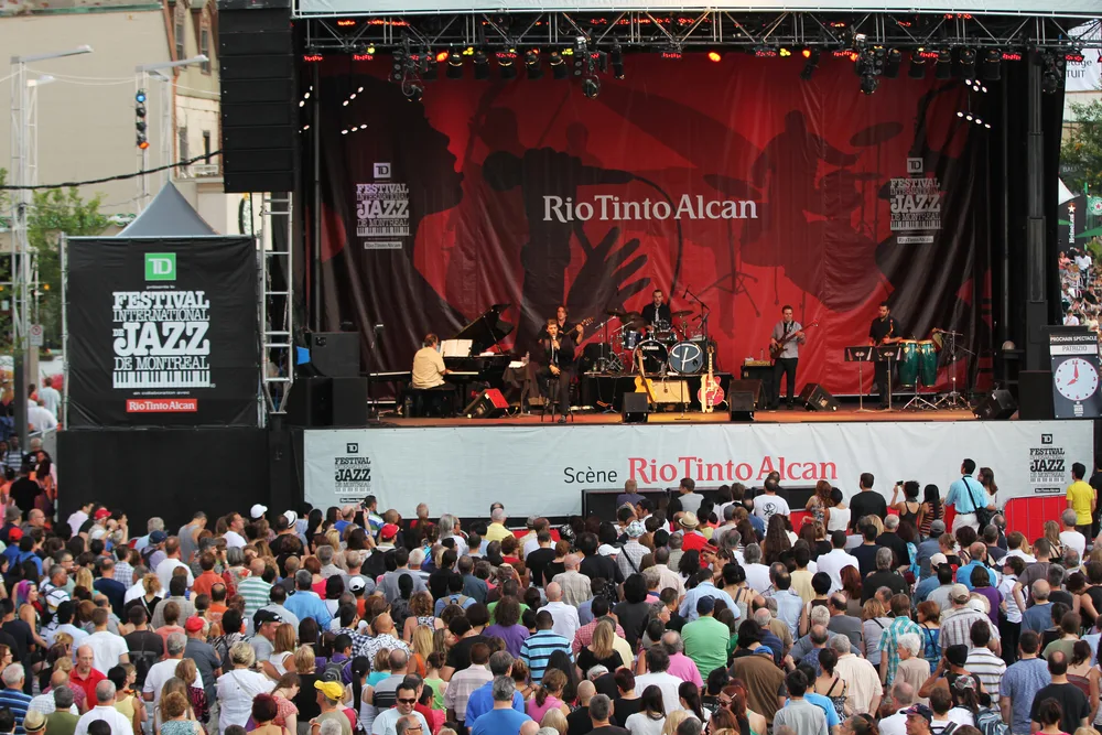 Many people gathered in a Jazz festival where a group is performing on stage during the best time to visit Montreal.