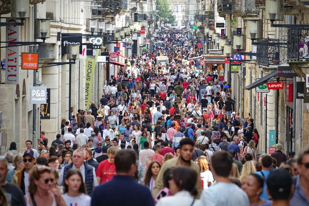 A street with buildings on each side and people can be seen shoulder to shoulder as they fill the street. 