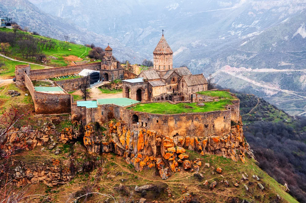 An old church built on the side of the mountain where huge rocks are piled to serve as its foundation, during the best time to visit Armenia.