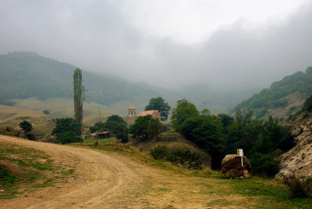 Pictured during the cheapest time to visit Armenia, the Church of St. Ogane in Ardi Village is seen with foggy mountains in the back