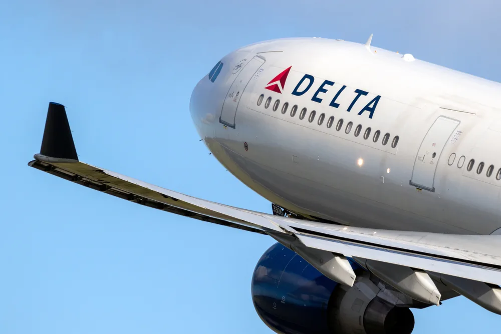 A Delta plane, in white color and a logo on the side, taking off for a flight to a Caribbean Island.