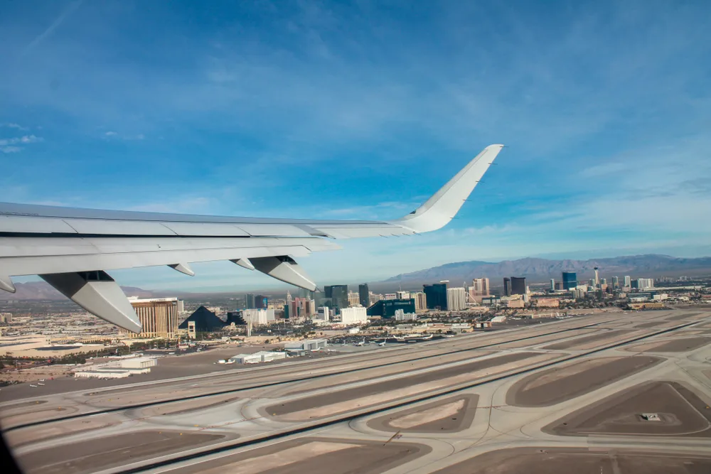 Airplane leaving MaCarran Airport in Las Vegas with views of the buildings in the distance for an article discussing how long is a flight to Vegas?