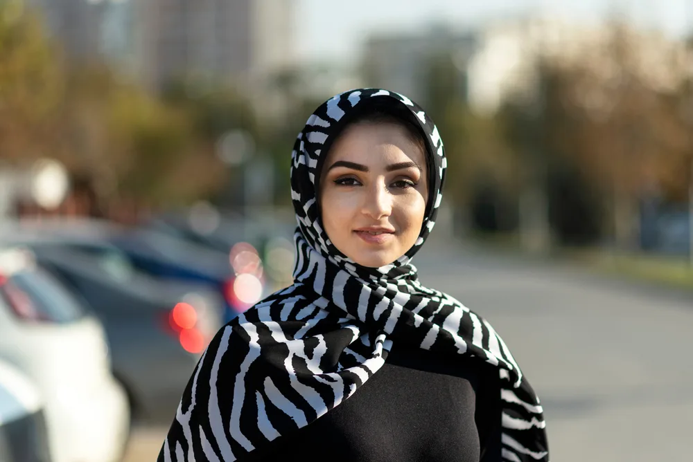 A portrait of a young Islam woman wearing white and black pattern head scarf. 