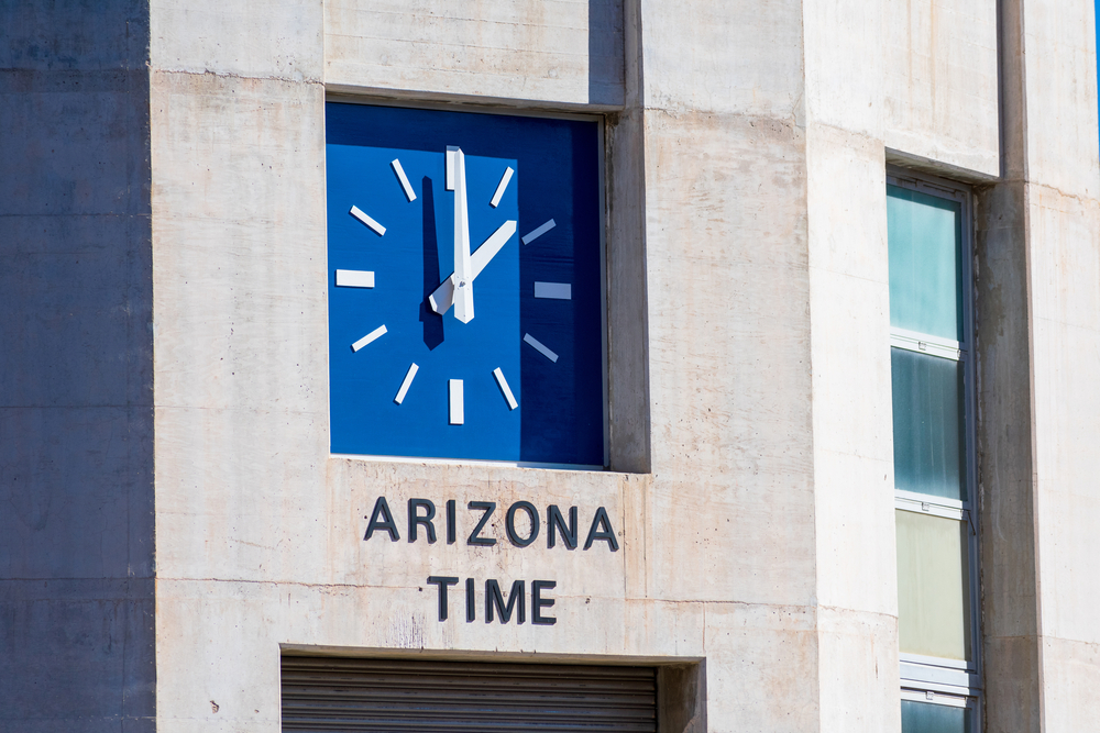 A huge clock on the building wall that points to 2 o'clock and has the label Arizona Time.