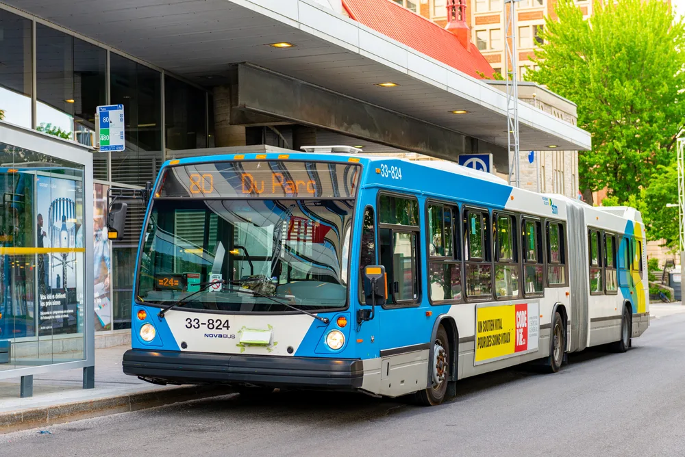 A large blue-white bus waiting for passengers in the bus stop, a concept image on the guide about the best time to visit Montreal.