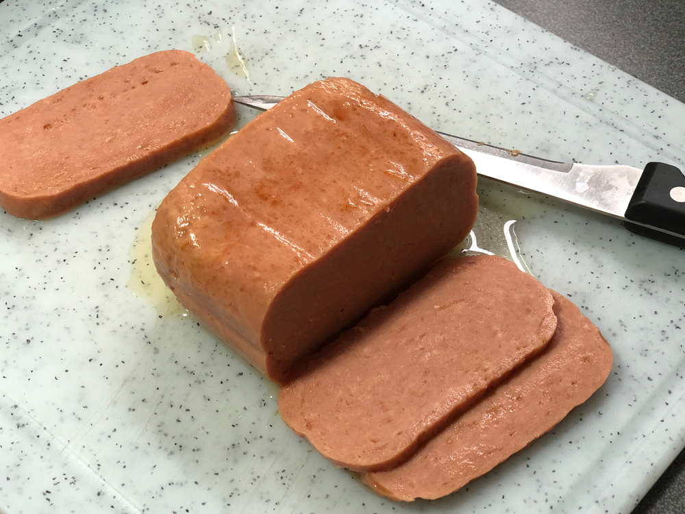 A can of Spam meat sliced on a cutting board for a frequently asked questions on why is Spam so popular in Hawaii?