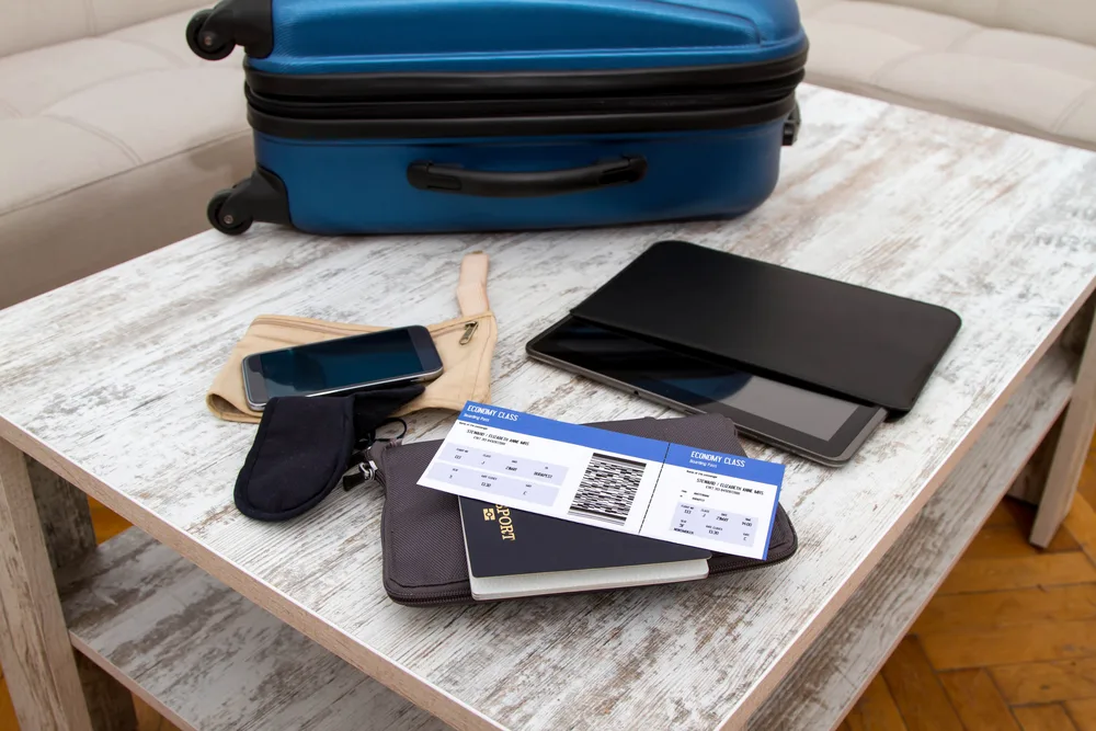 Travel documents placed on the table beside a blue luggage. 