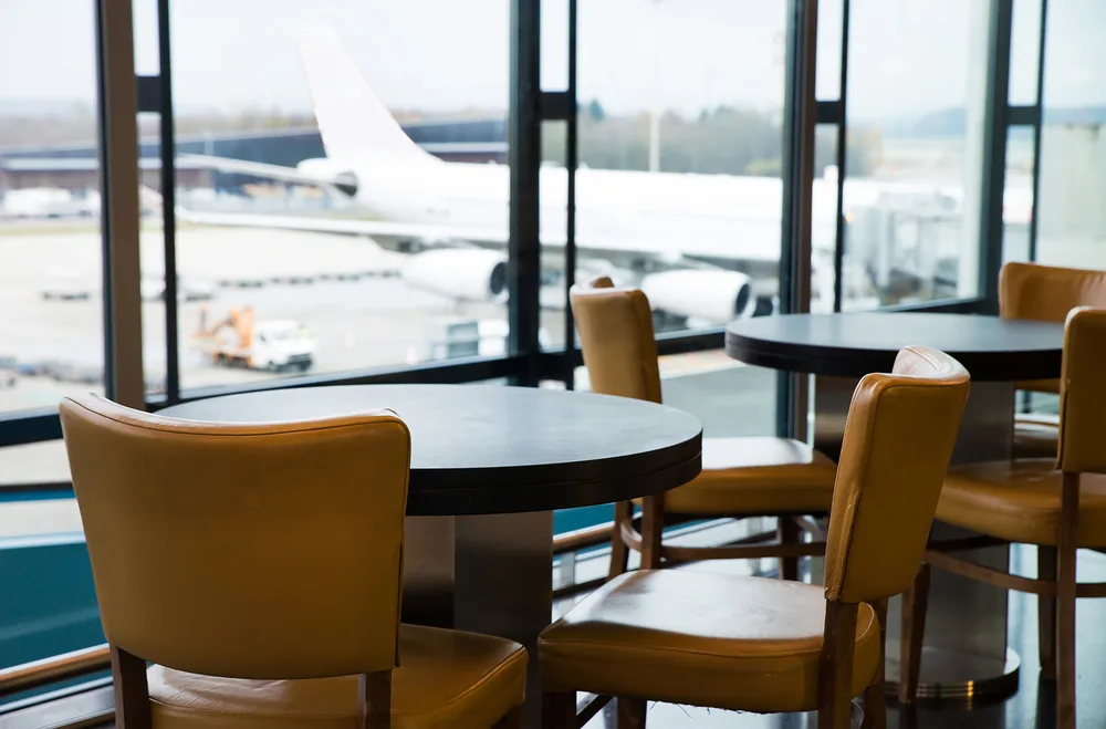 View of an empty table section inside an international airport lounge where people may wait during a stopover for a guide detailing what is a layover