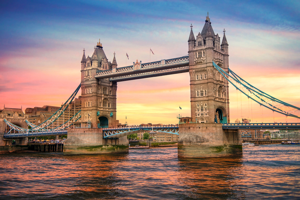 London's Tower Bridge shown during a colorful sunset with pink and blue skies reflecting on the Thames for a full Europe itinerary 2 weeks guide covering 3 classic, iconic cities