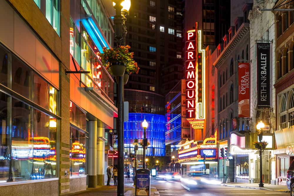 A night view of a street where on signage uses neon lights saying "PARAMOUNT", an image for the guide about the best time to visit Boston.