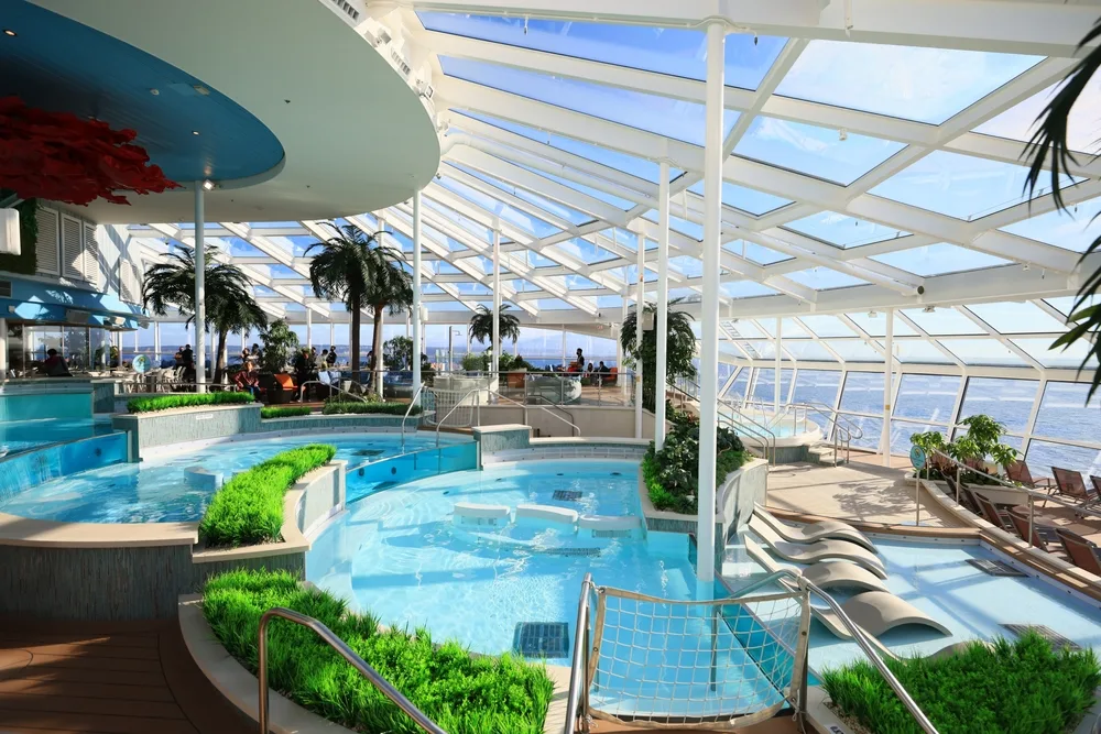 Inside a cruise ship with a swimming pool and sun beds overlooking the sea. 